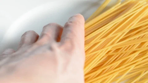 Taking raw spaghetti from white plate . Stock Footage 73620001