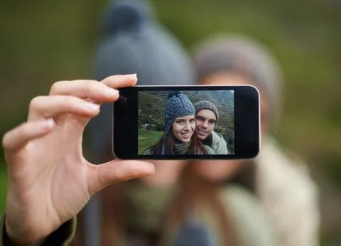 Taking a selfie on the mountains. A young couple taking a photo while hiking in Stock Photos