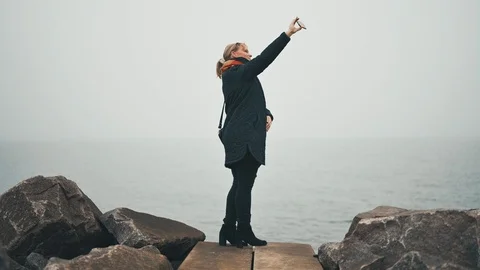 Taking selfie outside in poor and cold weather next to the sea Stock Footage 122259671