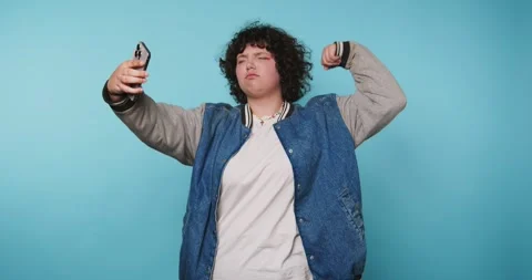 Taking selfies in front of a blue background with different poses and expre.. Vídeo Stock 328247558