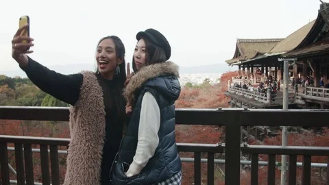 Taking selfies infront of beautiful temple in Kyoto overlooking city view Jap 스톡 동영상 70928747