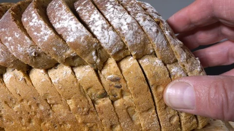 Taking slices of bread from a seeded loaf. Video stock 115507408