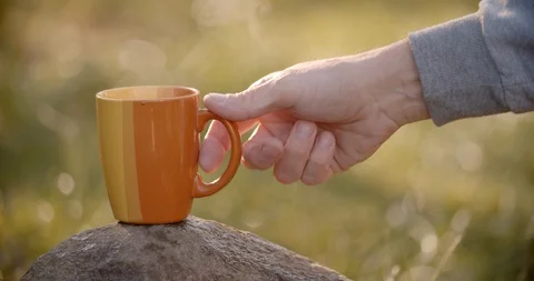 Taking a steaming cup with hot drink from the rock, countryside. Stock Footage 128325094