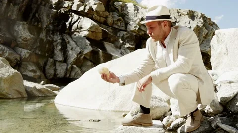 Taking stone out of water. stylish casual man. single alone. peaceful nature Video stock 42906939