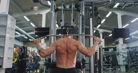 Taking video from the back young guy exercises hard on his gym class Video stock 116035702