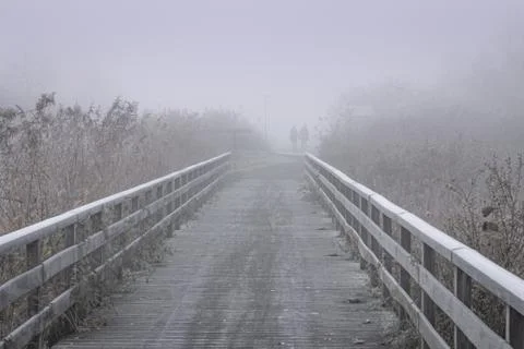 Taking a walk over the bridge on a cold and icy misty morning Stock Photos