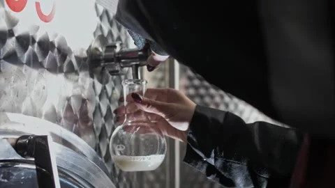 Taking a wine sample into a glass flask from a large wine fermentation tank Stock Footage 270057955