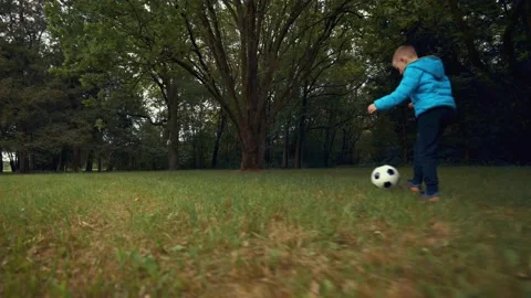 Talanted kid kicks the ball while running on the green lawn in the park. Stock-Footage 149240934