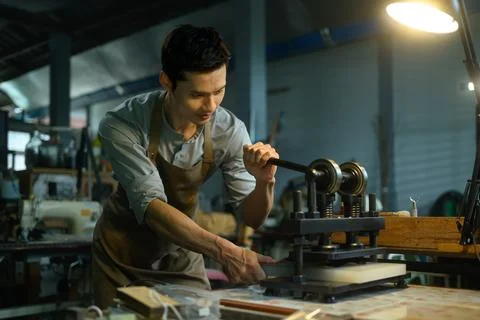Talented artisan using a manual press machine, working on a leather project in Stock Photos