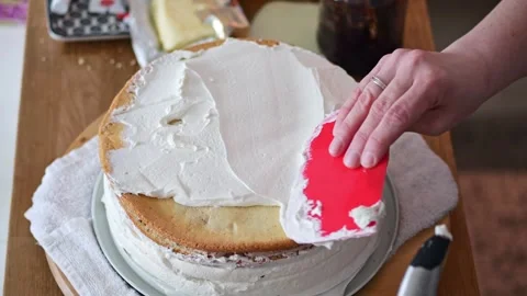 A talented baker delicately spreads layers of cream onto a birthday/wedding.. Stock Footage 240192809