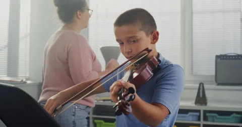 Talented Boy Playing Violin from Notes During Music Lesson. Teacher Training Видео 317538759