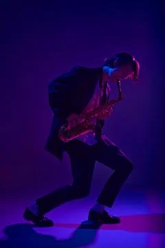 Talented jazz man, virtuoso playing saxophone in vibrant pink neon light against Stock Photos