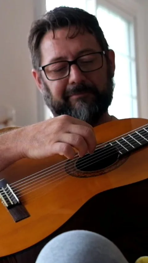 Talented middle-aged man with a beard and glasses playing a classical acoustic Stock Footage 344816034