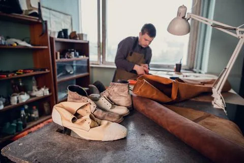 A talented shoemaker guy measures with a ruler and pencil, how much skin should Stock Photos