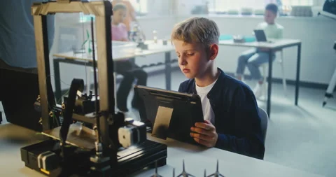 Talented Young Boy Writing Code for Automated 3D Printer on Digital Tablet in Stock Footage 311674371