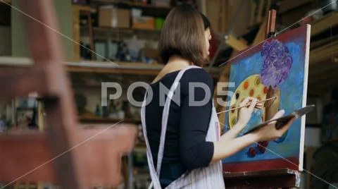 Talented young woman artist painting picture on canvas in art-class Stock Photos