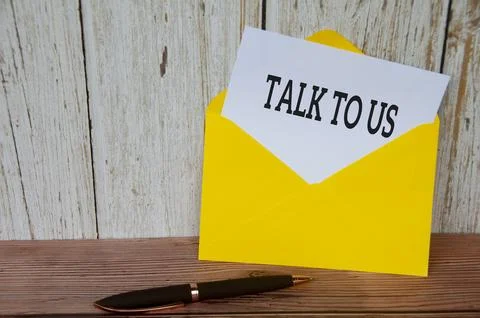 Talk to us text on white notepad in yellow envelope. Customer service concept Stock Photos
