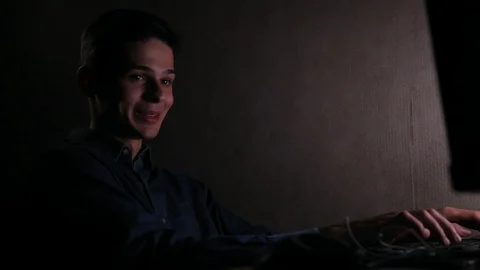 Talkative funny young man using computer in the room at night Видео 99051134