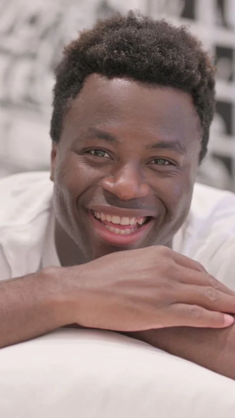 Talking African American Man Doing Video Chat while Lying on Stomach in Bed, Stock-Footage 328571483