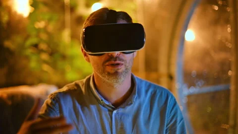 Talking man in VR glasses sitting inside a glamping tent with illumination at Stock Footage 250360666