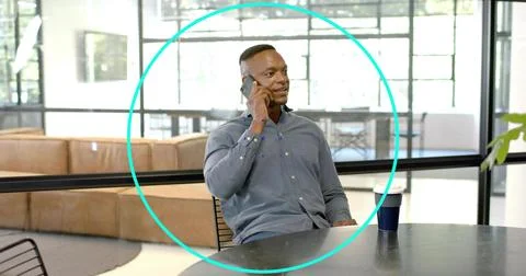 Talking man wearing button-down shirt holding smartphone to ear at office lounge Stock Photos