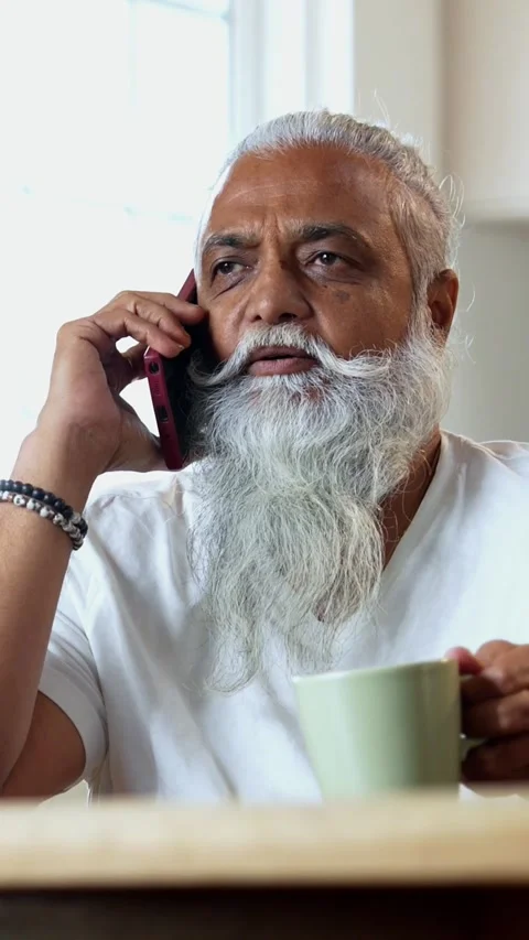 Talking on mobile phone at breakfast, stylish Indian mid age man in kitchen Stock Footage 342756783