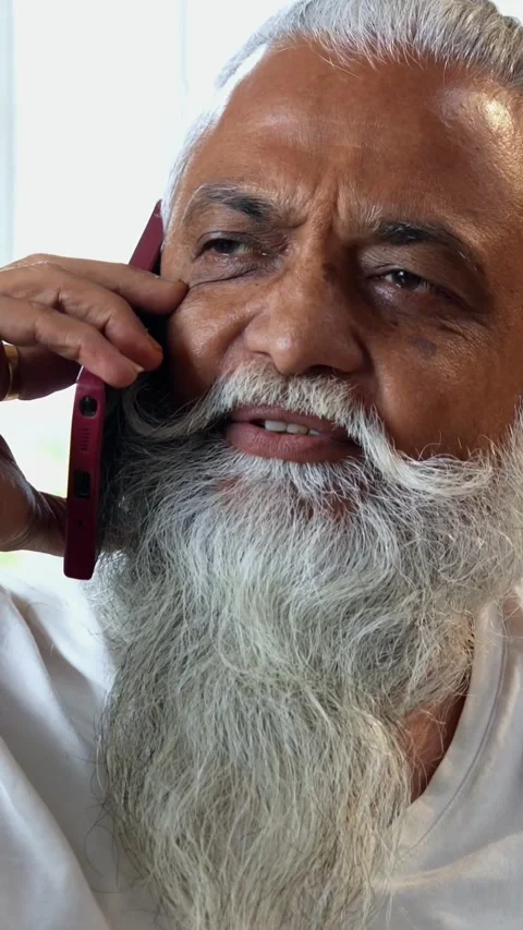 Talking on mobile phone at breakfast, stylish Indian mid age man in kitchen Video stock 342756795