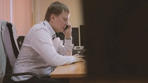 An talking on mobile phone whilst using computer Stock Footage 89669285