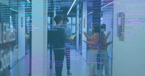 Talking team exchanging docs in office corridor, woman in rust sweater, yellow Stock Photos