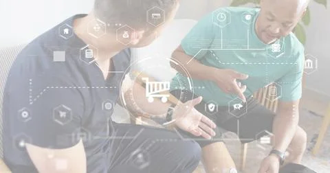 Talking two men wearing navy and teal tees, pointing at leg sensor in lounge, Stock Photos