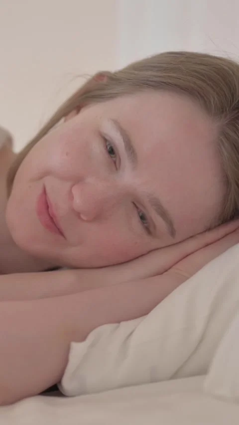 Talking Young Woman Lying in Bed on Side, vertical video Video stock 328564463
