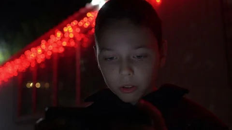 Talkitive kid playing mobile game at Christmas night, fair red lights bg, 4k  Video stock 98878886