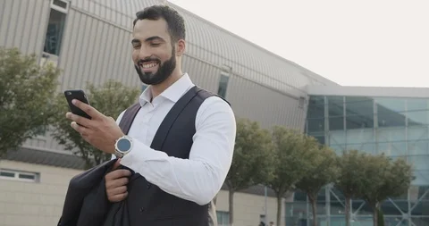 Tall Athletic Man passing time near huge Building. Using Smartphone, surfing Net Stock Footage 115658397