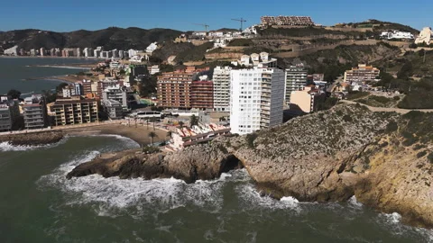 Tall beachfront buildings stand parallel with waves breaking along sandy coast Stock-Footage 308508128