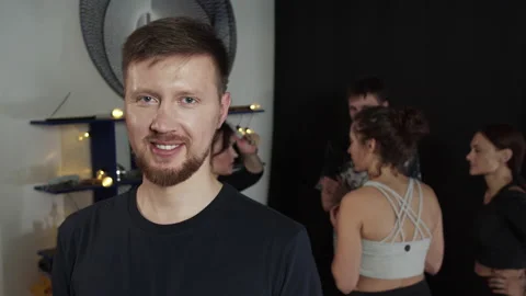 Tall bearded guy waving to the camera while people are chatting at the Stock Footage 157185985