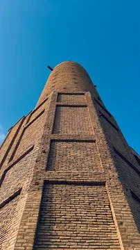 A Tall Brick Structure Under a Clear Blue Sky with a Unique Architectural D.. Stock Photos