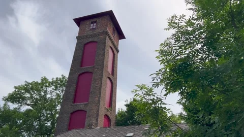 A tall brick tower with red window coverings stands against a partly cloudy. Video stock 301540420