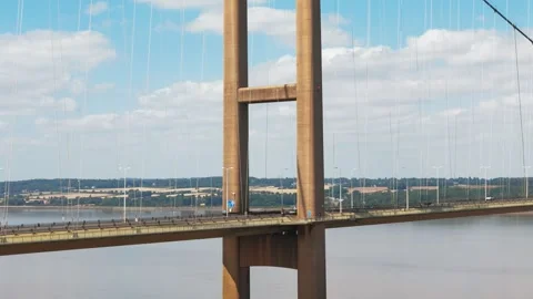 Tall bridge spans wide river under bright sky Vidéo 343545699