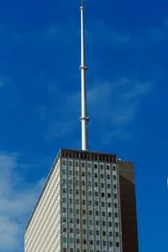 A tall building features a communication tower at its peak. The structure has Stock Photos