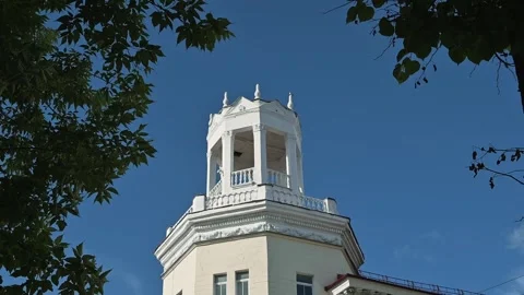 A tall building features a decorative tower with white trim and a clear blue sky 스톡 동영상 344527836