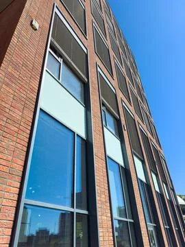 The tall building features large windows and a brick exterior. Sunlight refle Foto stock