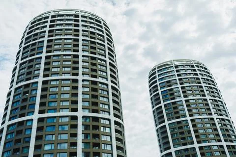 Tall buildings stand under a cloudy sky in an urban area, showcasing modern.. Stock Photos