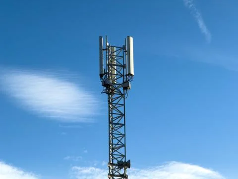 A tall cellular communication tower stands against a clear blue sky, capturing Stock Photos