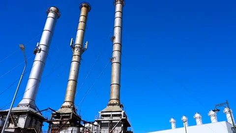 Tall chimneys against a clear blue sky on the territory of a factory, indus.. Stock Footage 340897018
