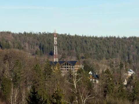 A tall communication tower rises above a wooden mountain hotel nestled within a Stock Photos