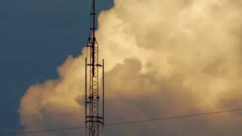 Tall communication tower structure standing against dramatic sunset sky with Stock Footage 348170050