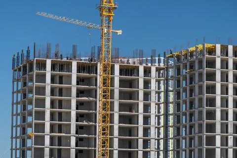 Tall concrete structures are taking shape under the bright sun. Workers are b 库存照片