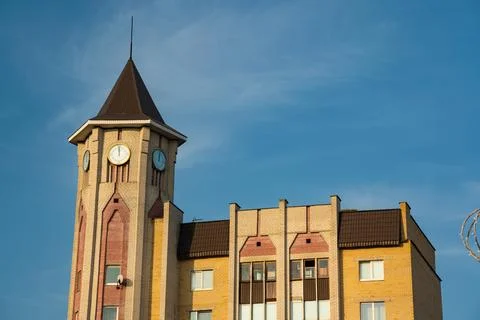 A tall, cone-shaped tower building in the city. Street clock on the tower Stock Photos