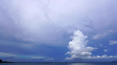 Tall cone tree shape cloud over ocean horizon Stock Photos