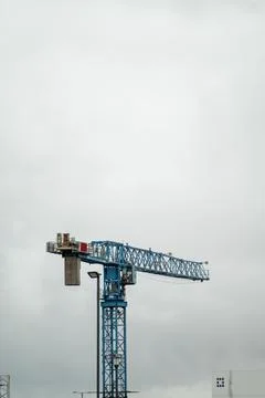 Tall construction crane against a cloudy sky. Building industry. Stock Photos